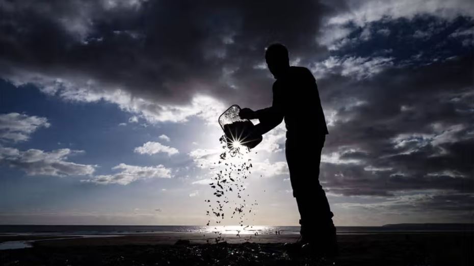 Man sprinkling microplastics on beach