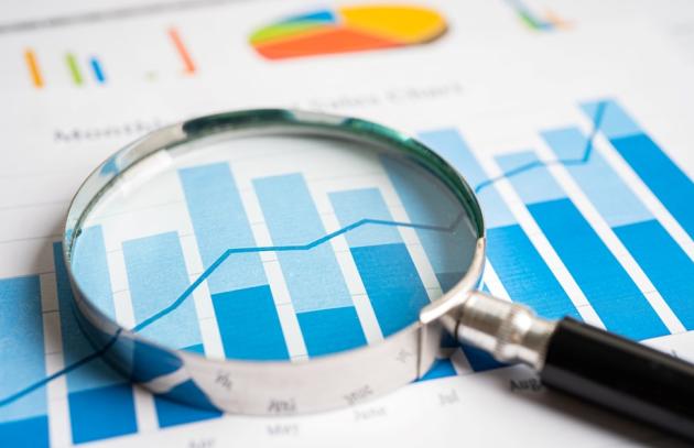 Magnifying glass laying on paper with bar graphs